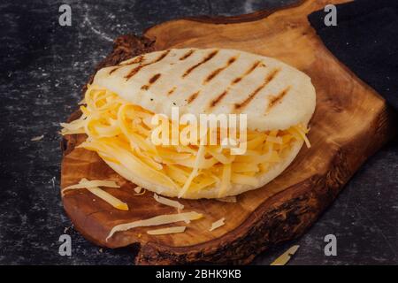 Arépa avec fromage jaune sur une planche en bois Banque D'Images