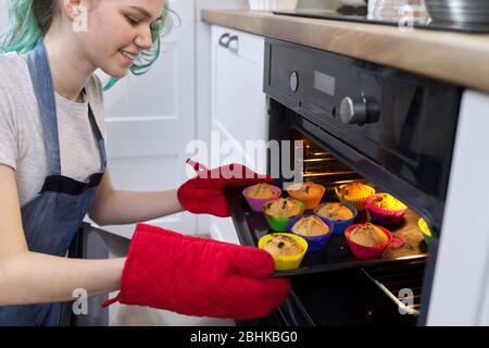 Fille adolescent nourriture blogger cuisine américaine cupcakes. Fille prenant des gâteaux avec des muffins chauds fraîchement cuits du four Banque D'Images