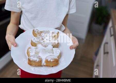 Fille enfant avec muffin fraîchement cuit saupoudrée de sucre glace. Cupcake sous forme de chat Banque D'Images