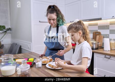 Enfants deux sœurs filles préparant des muffins dans la cuisine maison. Les enfants saupoudrer décorant des gâteaux faits maison fraîchement cuits avec de la poudre de sucre blanc Banque D'Images