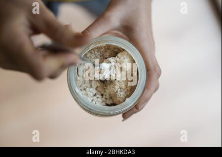 Vue de dessus de la femme qui allaite la levure de levain avec de la farine la mélangeant avec une cuillère. Banque D'Images