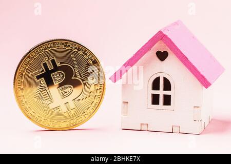 Maison de jouets et bitcoin sur fond rose. Concept d'investissement immobilier Banque D'Images