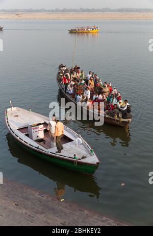 Un grand groupe de personnes prenant un tour en bateau dans la soirée pour voir la vue des ghats sur la rive de la rivière Ganges et venir près de la banque Banque D'Images