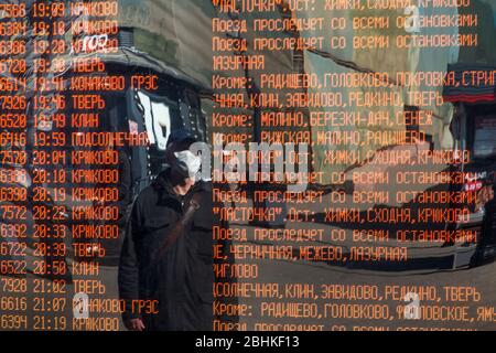 Un homme en masque de visage lit le panneau d'information avec le calendrier des trains de banlieue à la gare de Leningradsky à Moscou pendant la nouvelle épidémie de coronavirus de COVID-19 en Russie Banque D'Images