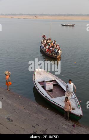 Un grand groupe de personnes prenant un tour en bateau dans la soirée pour voir la vue des ghats sur la rive de la rivière Ganges et venir près de la banque Banque D'Images