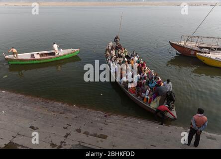 Un grand groupe de personnes prenant un tour en bateau dans la soirée pour voir la vue des ghats sur la rive de la rivière Ganges et venir près de la banque Banque D'Images