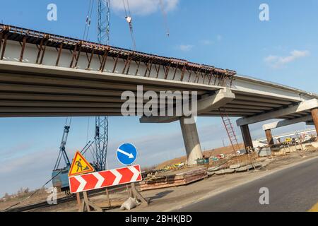 Nouveau pont routier moderne pont de passage supérieur site de contraste avec vue au-dessus de la chaussée avec des machines industrielles lourdes et ciel bleu sur fond. Ville urbaine Banque D'Images