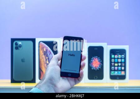Paris, France - 26 avril 2020: Homme tenant iPhone se avec le mot Hallo avec plusieurs paquets cardboards d'Apple Computers iPhone Smartphpone iPhone 3 gs, se 2016, XS et 11 Pro Banque D'Images