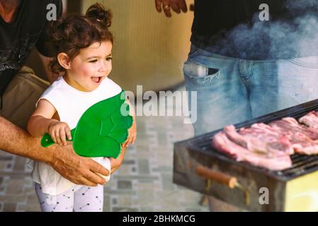 Barbecue père, grand-père et fille. Petit Chef griller de la viande avec sa jolie famille heureuse. Focalisation sélective sur les filles. Banque D'Images