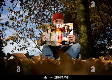 Un homme la lecture d'une copie du magazine FHM. Banque D'Images