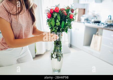 Femme prend le bouquet sec mort de fleurs de roses hors du vase. Femme de ménage prenant soin de la agrément sur la cuisine. Banque D'Images