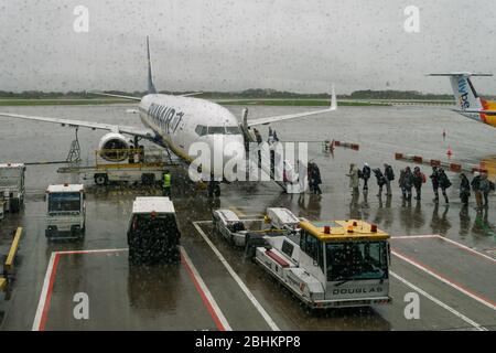 Manchester UK Ryanair avion avec passagers d'embarquement à l'aéroport tarmac. Vue par temps pluvieux sur les voyageurs dans la zone de tablier, entrant dans un Boeing 737-800. Banque D'Images