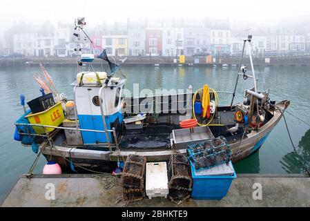 Un petit bateau de pêche industriel amarré à Weymouth chargé de pots de pêche. Banque D'Images