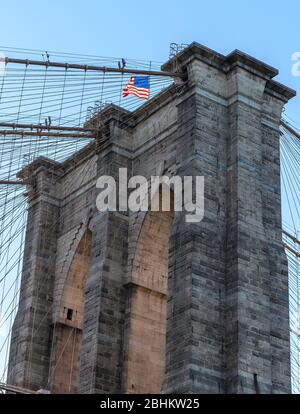 Pont de Brooklyn avec drapeau américain sur le dessus, ferme des arcs d'exposition. Banque D'Images