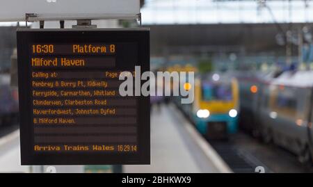 Information sur le départ du train à la gare de Manchester Piccadilly avec un train en arrière-plan Banque D'Images