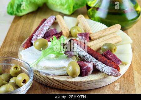 Saucisses Fuet chorizo, bâtonnets de pain, fromage, tranches de jamon et olives vertes sur la plaque de bois. Restauration rapide méditerranéenne. Banque D'Images