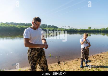 Père et fils qui étirent une canne à pêche avec du poisson sur le crochet. Banque D'Images