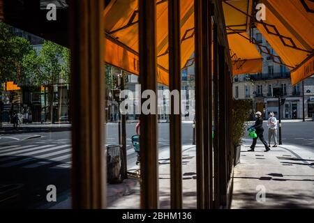 Paris, France. 26 avril 2020. Les personnes portant des masques de visage marchent devant un restaurant fermé à Paris, en France, le 26 avril 2020. La France a vu la mortalité de COVID-19 augmenter de 242 à 22 856 dimanche, la plus faible augmentation quotidienne de cette semaine, apportant des secours au système de santé du pays qui prévoit de lever le verrouillage le 11 mai, ont montré les données du Ministère de la Santé. Crédit: Aurelien Morissard/Xinhua/Alay Live News Banque D'Images