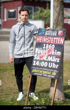 21 avril 2020, Bavaria, Kirchheim Bei München: Luca Beckenbauer, joueur de football de SV Heimstetten, se tient à côté d'une affiche sur le terrain d'entraînement du club annonçant un match entre SV Heimstetten et 1860 Rosenheim, qui a été annulé en raison du virus corona. Le quatrième joueur de la ligue de 19 ans est le petit-fils de la légende du football Franz Beckenbauer. Photo : Matthias Balk/dpa Banque D'Images