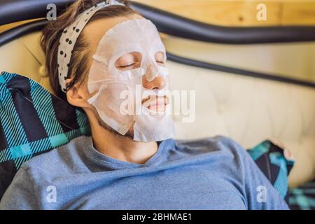 Jeune homme faisant une feuille de masque facial. Concept de beauté et de soins de la peau Banque D'Images