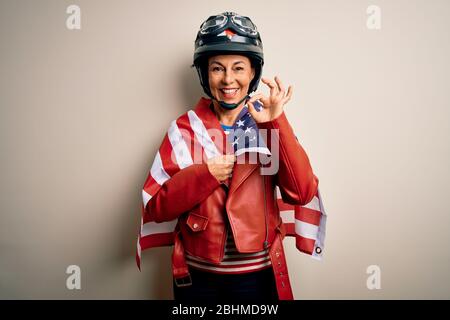 Femme motards d'âge moyen portant un casque de moto et drapeau des États-unis faisant bon signe avec les doigts, excellent symbole Banque D'Images