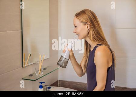 Femme utilisant un irrigateur oral dans la salle de bains Banque D'Images