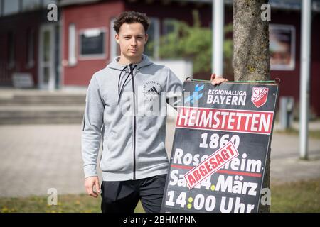 21 avril 2020, Bavaria, Kirchheim Bei München: Luca Beckenbauer, joueur de football de SV Heimstetten, se tient à côté d'une affiche sur le terrain d'entraînement du club annonçant un match entre SV Heimstetten et 1860 Rosenheim, qui a été annulé en raison du virus corona. Le quatrième joueur de la ligue de 19 ans est le petit-fils de la légende du football Franz Beckenbauer. Photo : Matthias Balk/dpa Banque D'Images