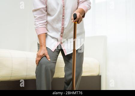 Douleur de genou de la femme senior avec bâton, problème de santé de concept senior Banque D'Images