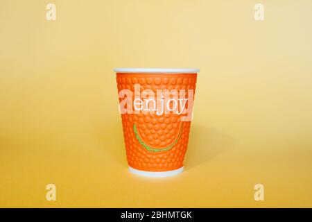 Mug en papier orange avec les mots appréciez et souriez sur un fond jaune vif Banque D'Images