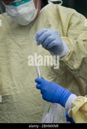 Drive – via les tests COVID-19, Medford, Massachusetts, États-Unis. 25 avril 2020. Technicien médical plaçant un écouvillon nasal dans le tube à essai chez PhysicianOne urgent Care. Banque D'Images