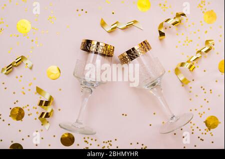 Deux verres en verre avec bordure dorée sur fond rose avec décorations dorées, sequins, étoiles, rubans en feuille et grand noeud doré pour pa Banque D'Images