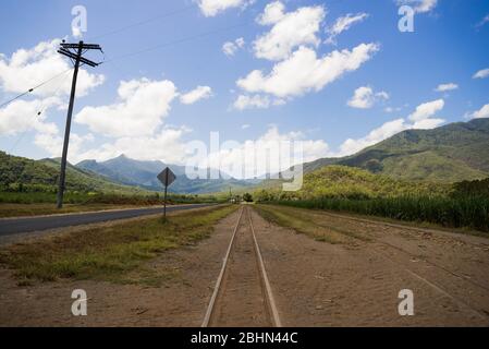 Une route en Australie qui est vide près de cairns avec les poteaux téléphoniques de l'arrière-pays et une route de terre avec des voies de train Banque D'Images