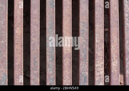 Grille en fer sur le canal de drainage sur la route. Texture rouillée et éraflures sur le métal. Horizontal. Banque D'Images