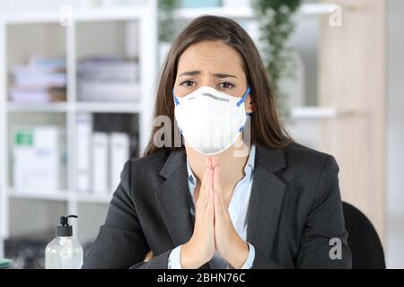 Vue de face de la femme de direction avec masque de protection mendiant regardant la caméra au bureau Banque D'Images