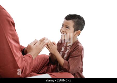 Un garçon musulman s'excuse lorsqu'il célèbre avec son père l'Eid UL-Fitr heureux Banque D'Images