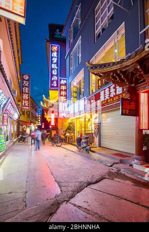 Lijiang, Chine - 27 septembre 2017: Rue de Lijiang zone touristique illuminée par des panneaux publicitaires avec des personnages chinois la nuit. Banque D'Images