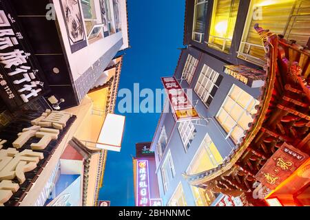 Lijiang, Chine - 27 septembre 2017: Recherche de bâtiments avec des panneaux publicitaires avec des personnages chinois la nuit. Banque D'Images