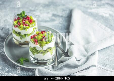 Deux verres repas sain en granola sur la plaque grise, le yaourt et les fruits kiwi. Délicieux repas pour le petit déjeuner. Collation américaine traditionnelle. Banque D'Images