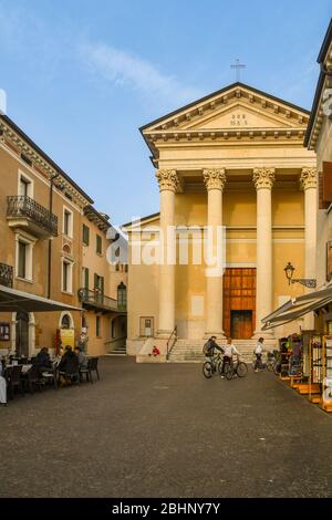 Vue sur le centre historique de Bardolino avec l'église paroissiale de St Nicolò et St Severo avec un porche néoclassique et des gens dans le café extérieur, Italie Banque D'Images