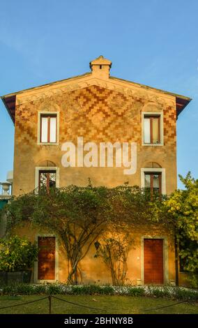 Extérieur d'une ancienne villa de vacances avec des plantes grimpantes et un motif géométrique en briques sur la façade, Bardolino, province de Vérone, Vénétie, Italie Banque D'Images