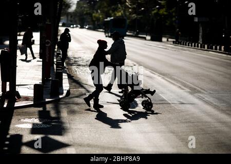 Bucarest, Roumanie - 22 avril 2020: Silhouettes de personnes traversant une route dans le centre de Bucarest pendant le verrouillage covid-19 au crépuscule. Banque D'Images