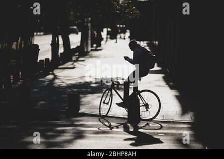 Bucarest, Roumanie - 22 avril 2020: Silhouette d'un cycliste sur une route dans le centre de Bucarest pendant le verrouillage du covid-19 au crépuscule. Banque D'Images