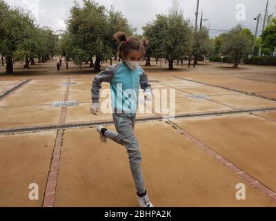 Fille de neuf ans, portant un masque de 95 ans, courir dans la rue Banque D'Images