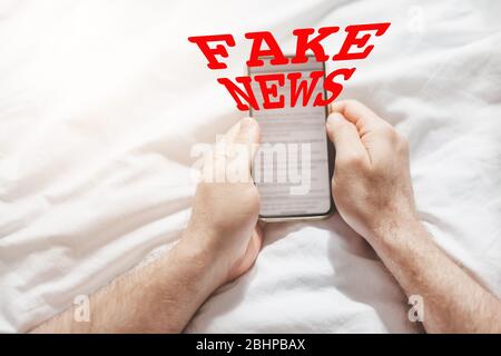 Fausses nouvelles infodemics pendant le concept de pandémie de Covid-19. Les mains de l'homme tenant le téléphone mobile lire les nouvelles mondiales ou le réseau social à la maison. Lire la dernière actualité Banque D'Images