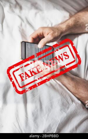 Fausses nouvelles infodemics pendant le concept de pandémie de Covid-19. Les mains de l'homme tenant le téléphone mobile lire les nouvelles mondiales ou le réseau social à la maison. Lire la dernière actualité Banque D'Images
