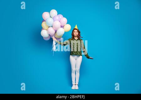 Photo pleine taille de jolie drôle dame tenir beaucoup de ballons d'air colorés meilleur anniversaire fête coup noisemaker porter anniversaire casquette pointillé chemise blanc pantalon Banque D'Images