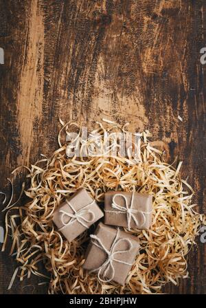 Petites boîtes-cadeaux rustiques sur fond texturé en bois avec espace pour le texte. Vue de dessus Banque D'Images