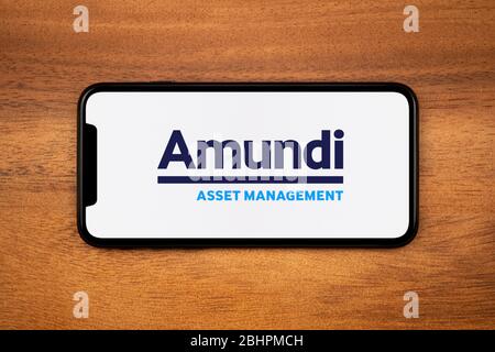 Un smartphone affichant le logo Amundi Asset Management repose sur une table en bois ordinaire (usage éditorial uniquement). Banque D'Images