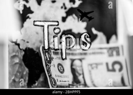 Un bol en plastique avec une facture de cinq dollars. Sur le fond d'une silhouette d'avion noir et de la carte du monde. Noir et blanc. Banque D'Images