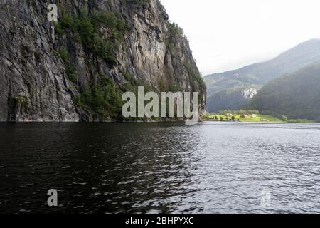 Immense montagne et vue sur le village de Mo pendant la croisière sur le fjord de Mostraumen au départ de Bergen, Norvège Banque D'Images